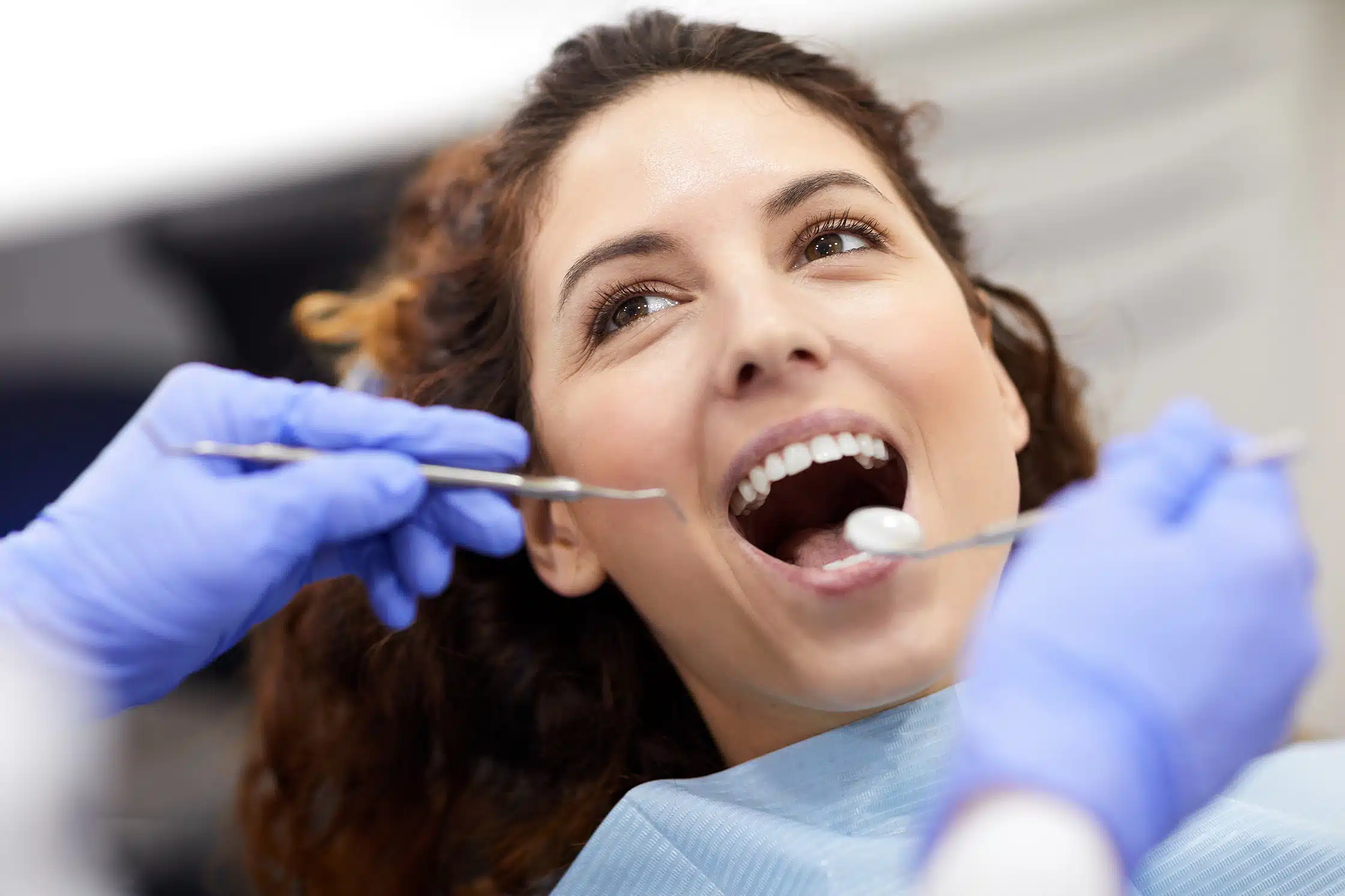 woman smiling getting teeth cleaned - Trail West Family Dentistry